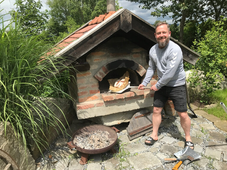 Ein Mann steht vor einem gemauerten Ofen.