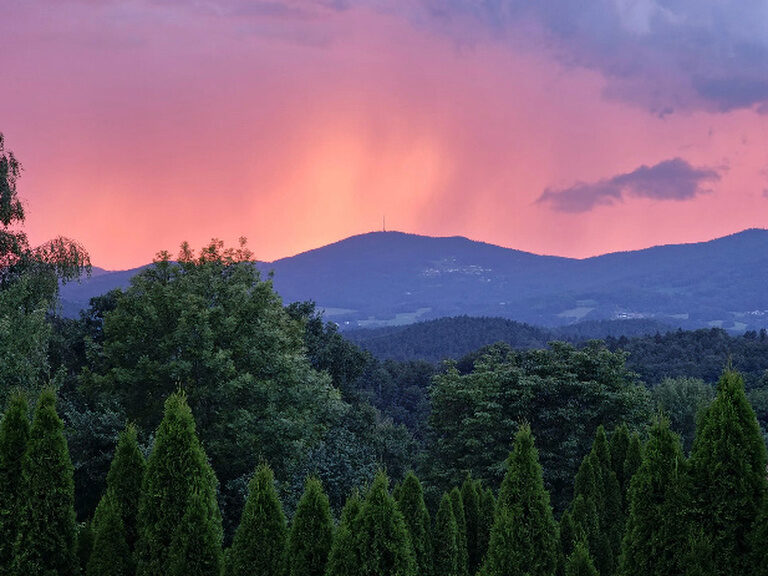 Die untergehende Sonne färbt den Himmel über dem Brotjacklriegl in pinkes Licht